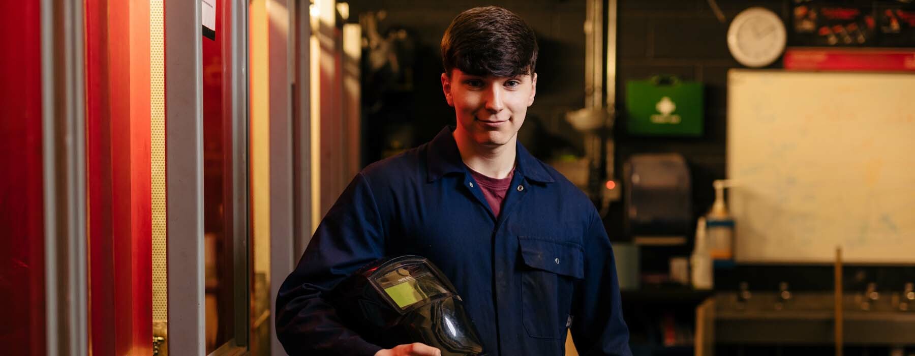 Apprenticeships banner Engineering apprentice holding protective face mask for welding