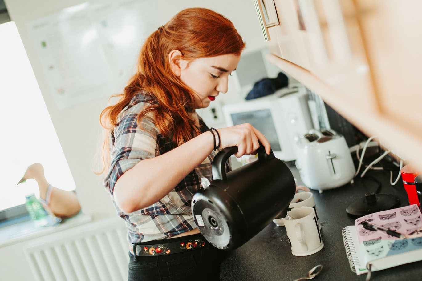 Female student making a cup of tea in kitchen