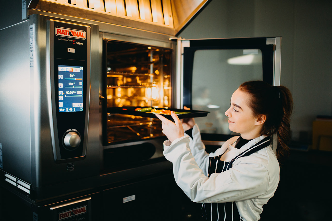 Food callout Professional cookery student placing vegetables into the oven
