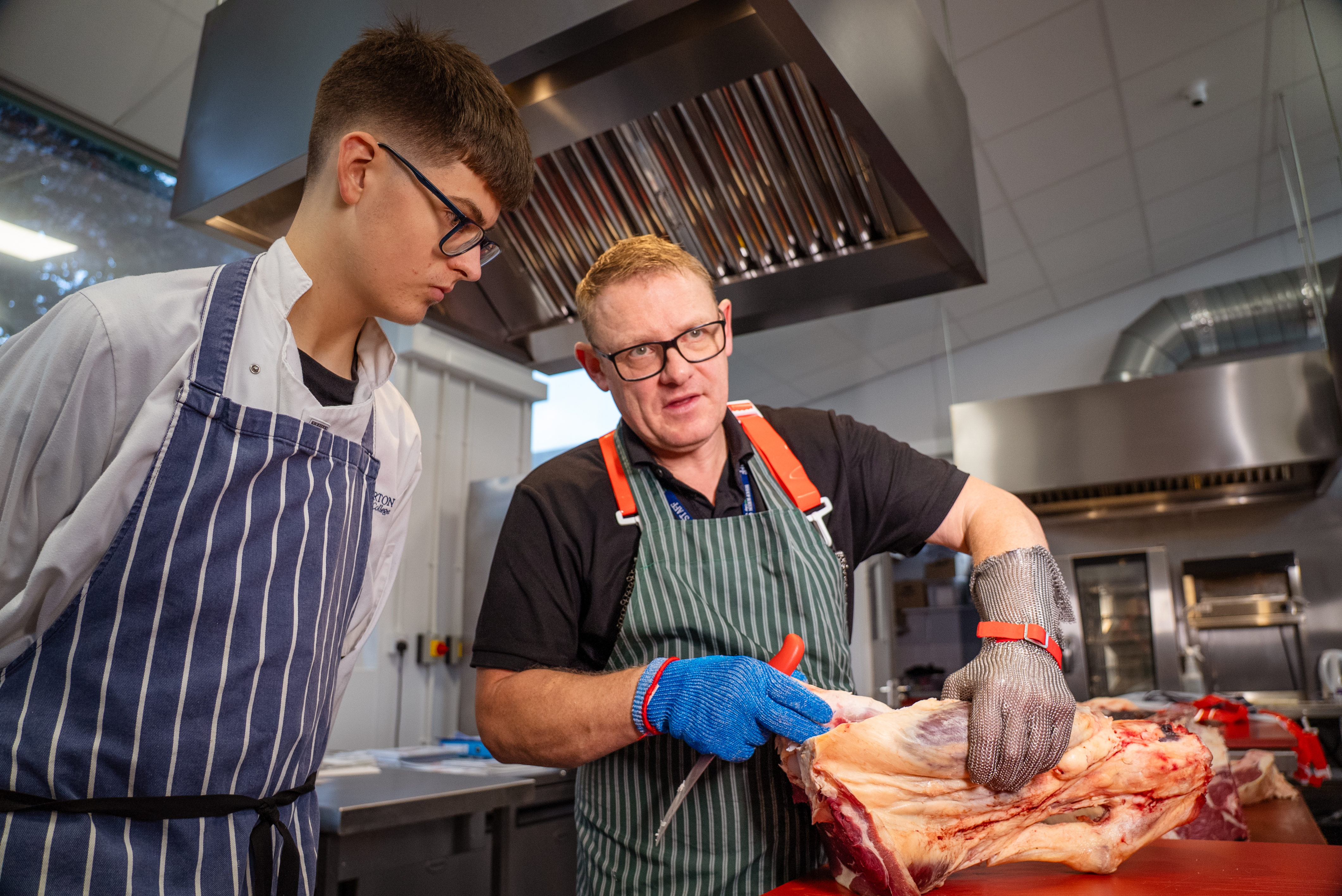 Teacher showing apprentice joint of meat